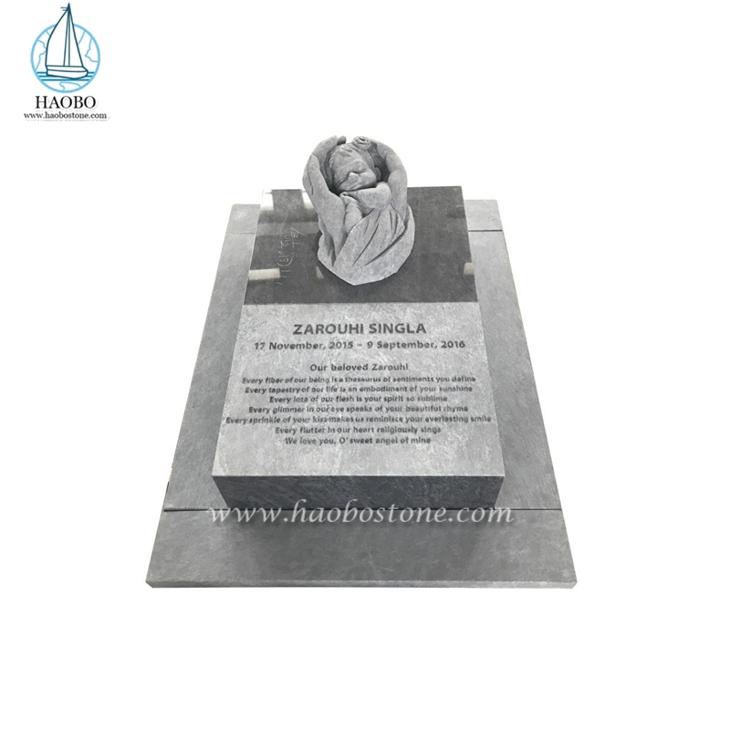 Main de granit gris adaptée aux besoins du client tenant le monument de marqueur sculpté par ange de bébé
